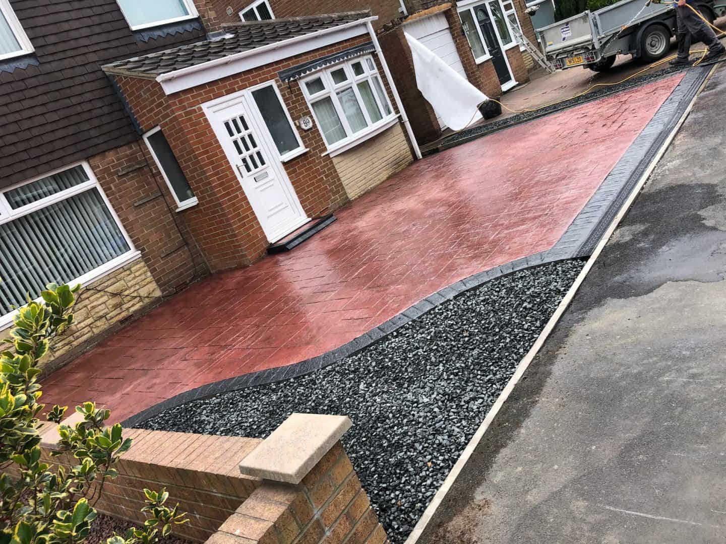Red pattern imprinted concrete driveway with a charcoal border and a slate chipping bed — The Vale Company